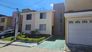 A residential building with a garage, a driveway, and a small garden area. - Casa Nimajay (Guatemala City)