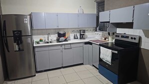 A compact kitchen with a refrigerator, microwave, stove, and sink. - Casa Nimajay (Guatemala City)
