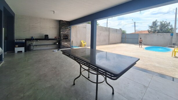 Un espace intérieur spacieux comprenant une cuisine, une table à manger et donnant sur une cour arrière avec une piscine.
