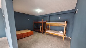 Une chambre avec deux lits superposés, un lit simple et un sol carrelé.