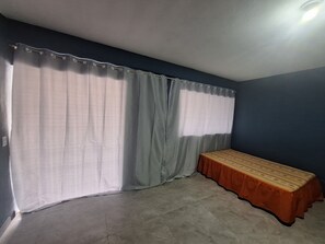 Une pièce avec un lit, des rideaux et un luminaire au plafond.