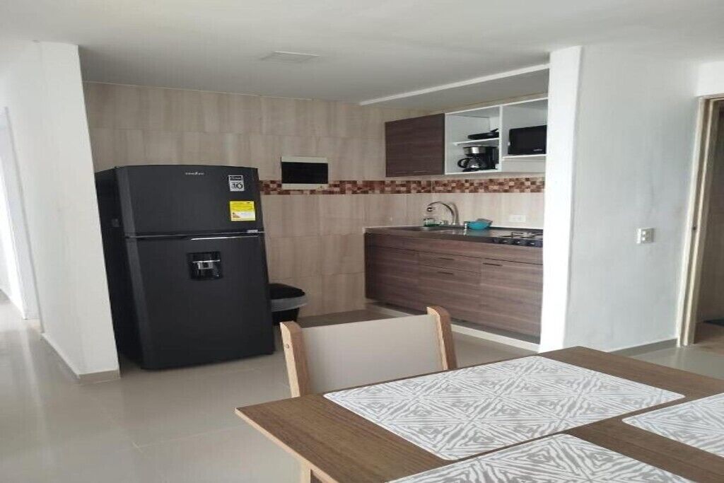 A compact kitchen with a black refrigerator, wooden cabinets, a microwave, and a sink.