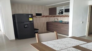 Une cuisine de taille réduite, avec un réfrigérateur noir, des placards en bois, un four à micro-ondes et un évier.
