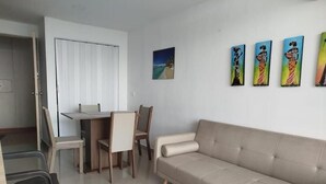 Un salon avec un canapé, une table à manger et des chaises, et un tableau accroché au mur.