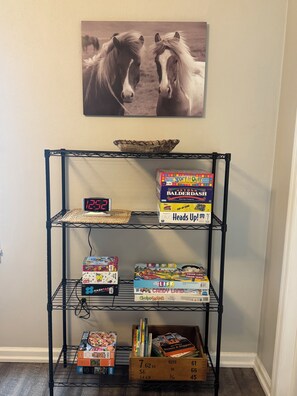 A shelf with board games, a clock, and a framed picture of horses. - 3BR Near Versailles, Friendship, and Madison (Versailles)