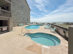 A pool area with two pools, lounge chairs, and a wooden deck. - Maritime Place A5 - Oceanfront in Garden City Beach (Garden City Beach)