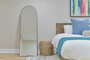 A bedroom with a bed, a large mirror, a wicker basket, and a colorful abstract painting on the wall. - Spacious 4BR near Northwestern with King Beds + Crib (Evanston)