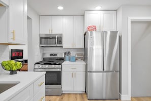 A modern kitchen with white cabinets, stainless steel appliances, and a visible 'Netflix' sign. - Spacious 4BR near Northwestern with King Beds + Crib (Evanston)