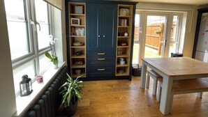 A kitchen with a wooden table, a built-in bookshelf, and a window with a view of the outside. - Entire Home. 3 bedroom house in Edinburgh suburb (Edinburgh)