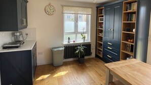 A kitchen with dark cabinets, a window with a view, a radiator, and a bookshelf. - Entire Home. 3 bedroom house in Edinburgh suburb (Edinburgh)