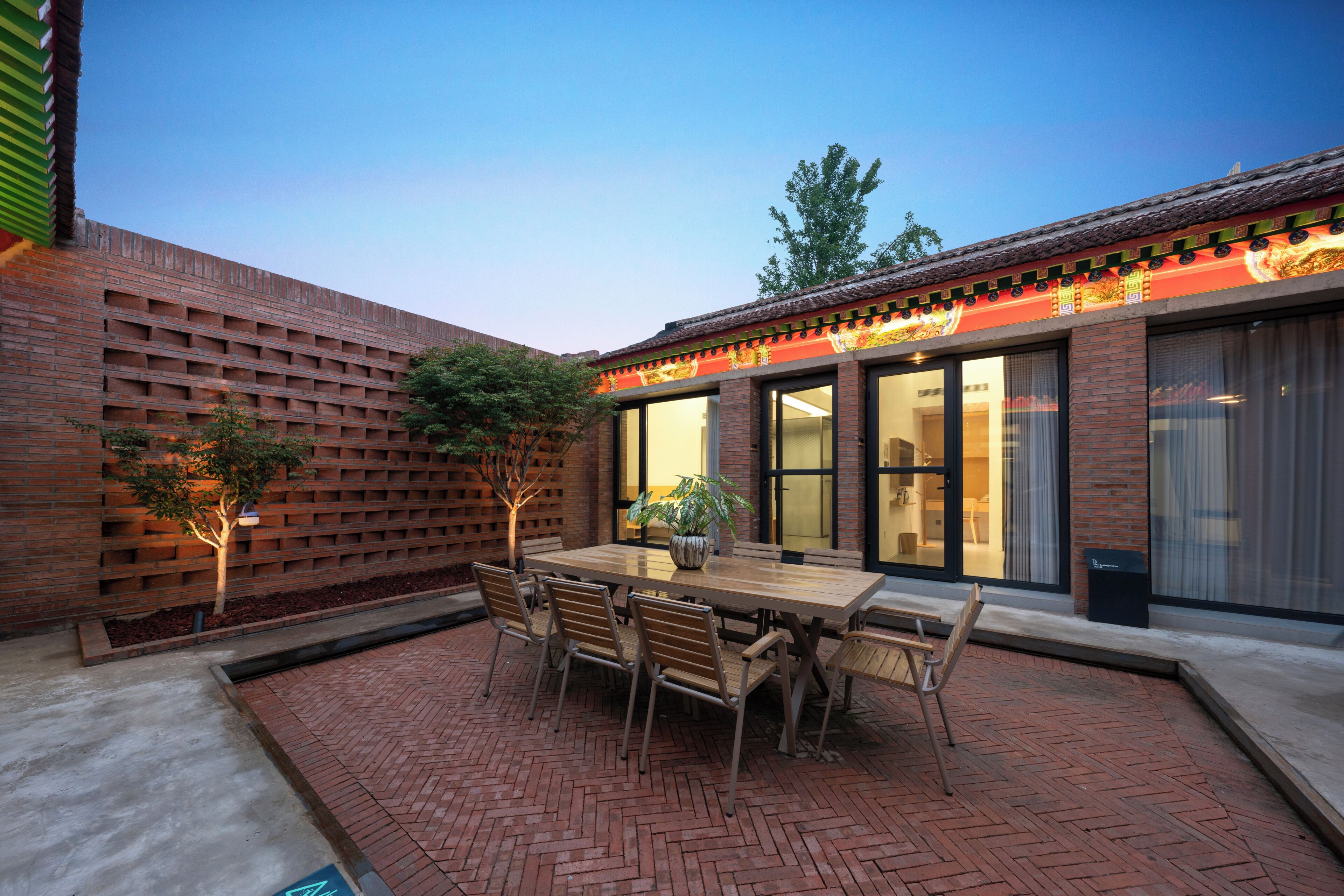 A patio with a brick floor, a wooden table, and chairs.