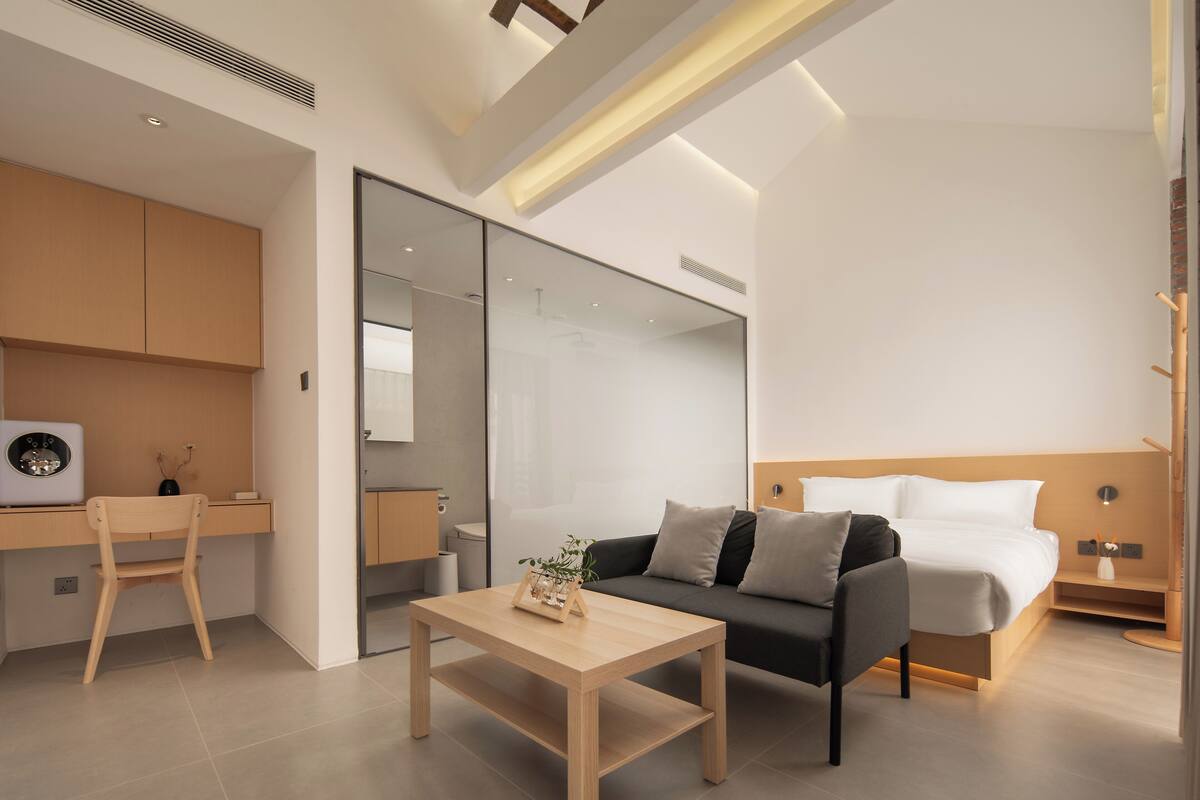A modern hotel room with a bed, a desk, a chair, and a coffee table.