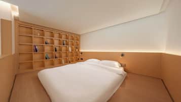 Un dormitorio con una cama grande, estantería de madera y una lámpara fijada a la pared.