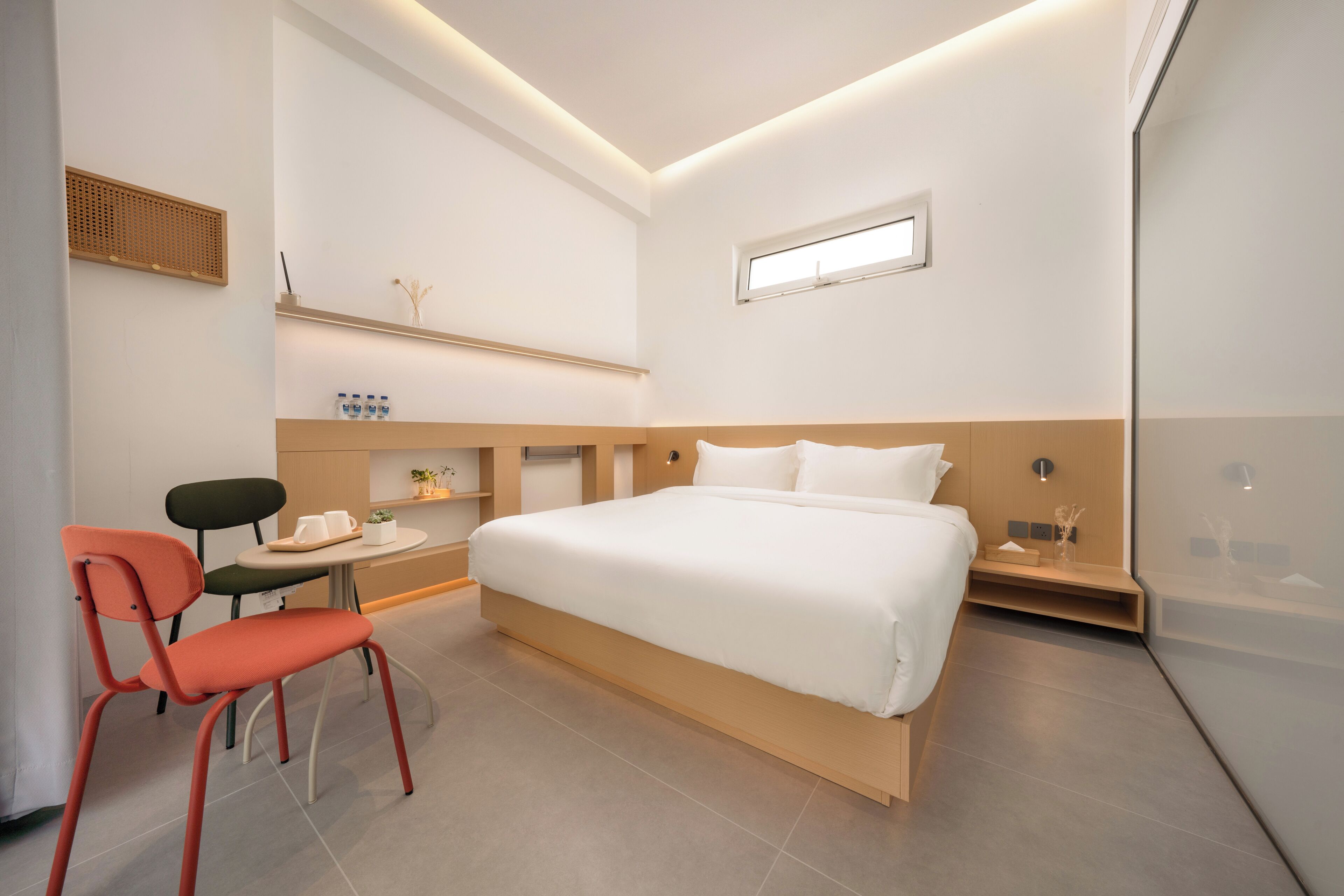 Ein modernes Schlafzimmer mit einem Bett, einem Schreibtisch, zwei Stühlen und einem kleinen Tisch.