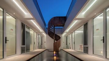 Un edificio moderno con una escalera espiral central, puertas de cristal y una piscina.