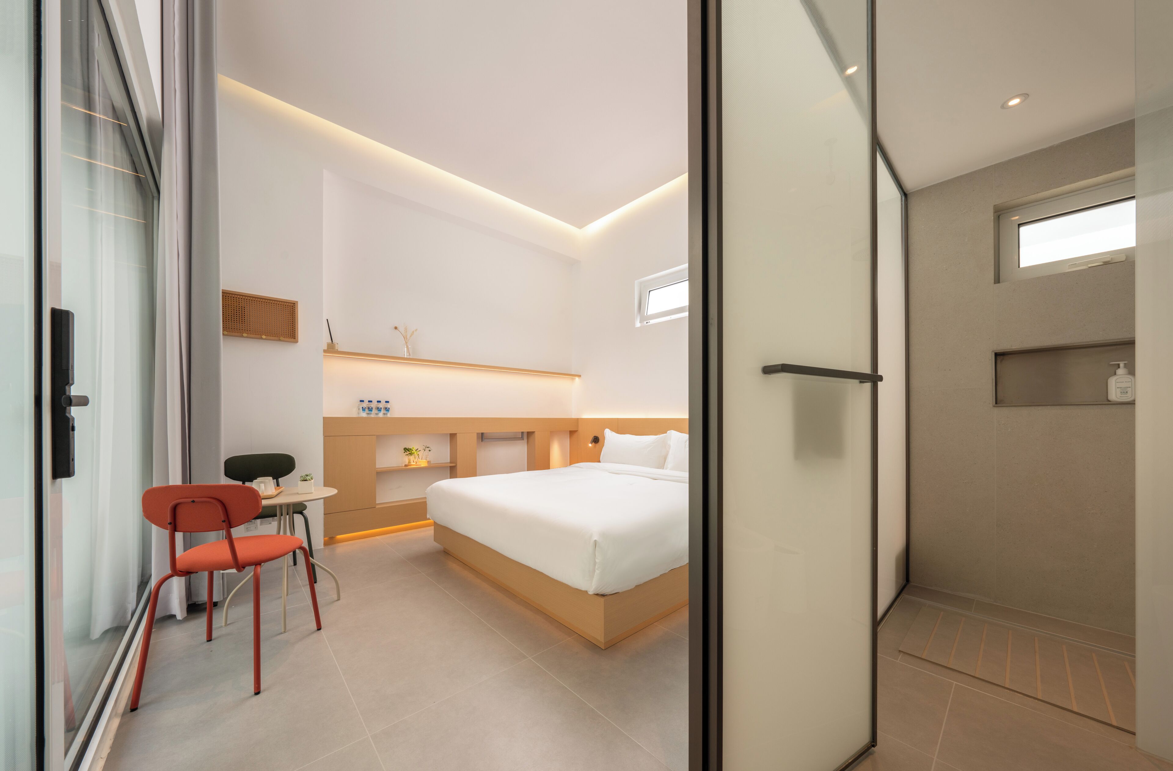 A modern hotel room with a bed, a desk, and a chair.