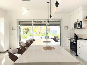 A modern kitchen with a large island, stainless steel appliances, and a view to the outdoors. - Luxury Grace Bay Villa 3, 100 steps to Beach&reef, private pool for 6 (The Bight Settlement)