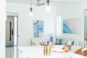 Ein modernes Wohnzimmer mit einer großen Couch, einem Esstisch und Kunstwerken an den Wänden.