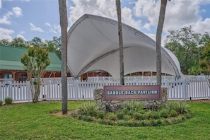 A pavilion with a sign reading 'Saddleback Pavilion' surrounded by a white picket fence and palm trees. - The Covered Corral Luxury RV Lot River Ranch 253 (Lake Wales)