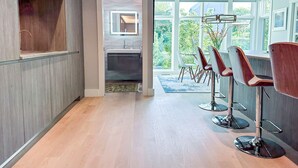 Een modern interieur met een keuken, eethoek en grote ramen met uitzicht op groen.