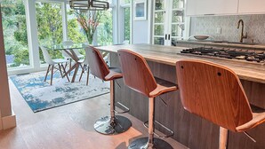 Een moderne keuken met een groot eiland, barkrukken en uitzicht op groen.