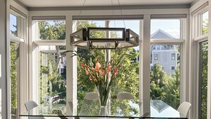 Een moderne eetruimte met een glazen tafel, witte stoelen en een vaas met bloemen.