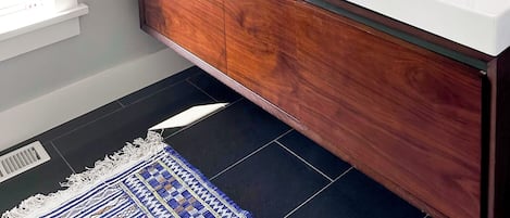 Un baño con lavamanos doble, tocador de madera, un espejo grande y cuadros en la pared.