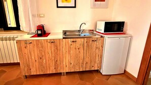 Una cocina compacta con un lavamanos, un microondas y una cafetera.