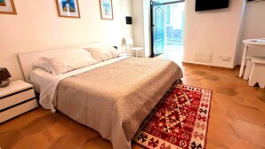 Un dormitorio con cama, una silla, un escritorio y una televisión en la pared.