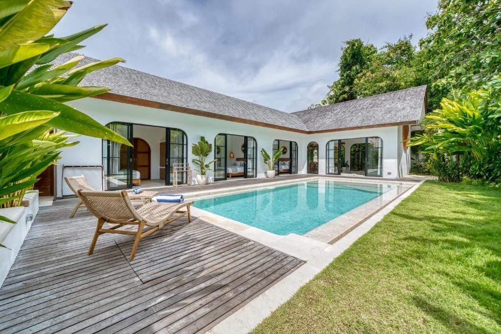 A modern house with a swimming pool, a wooden deck, and a well-maintained lawn.