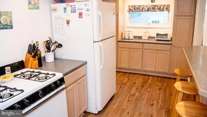 Una cocina con estufa a gas, refrigerador blanco, armarios de madera y una ventana con vistas.