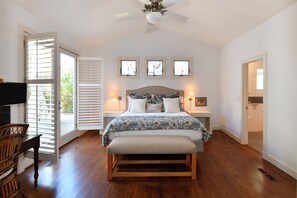 Une chambre à coucher comprenant un lit, des tables de chevet, un bureau, une chaise et un ventilateur de plafond.