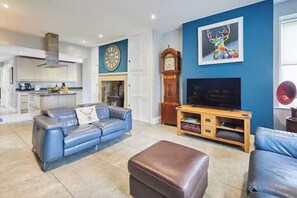 Un salon comprenant un canapé, un pouf, un meuble pour la télévision et une cheminée.