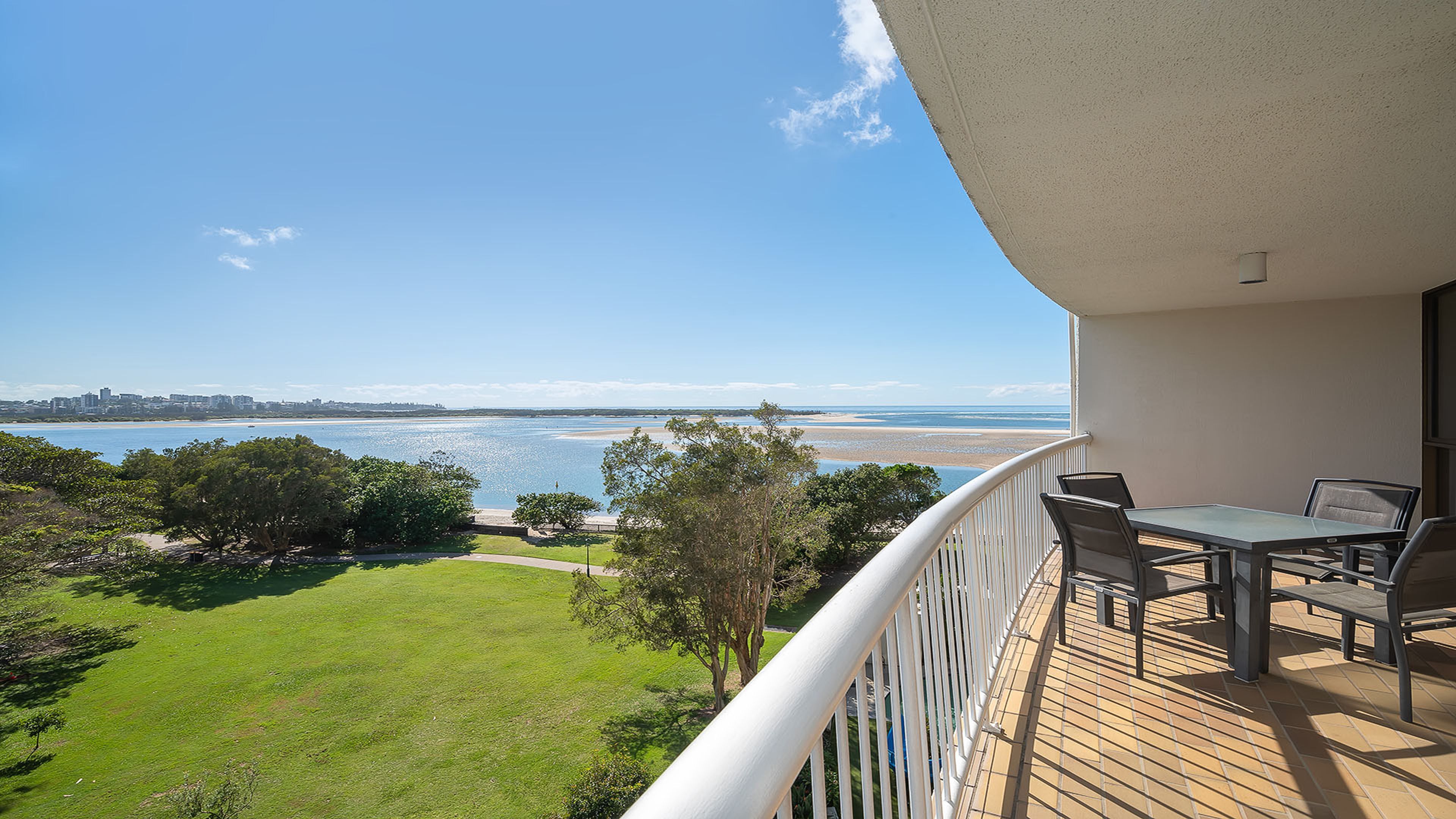 A balcony with a view of the sea and a grassy area.