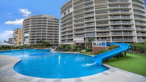 A swimming pool with a slide, surrounded by multi-story residential buildings. - Gemini Resort 55 Stunning Ocean Views (Golden Beach)