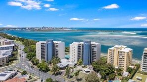 A high-rise hotel with multiple floors, a parking area, and a view of the ocean. - Gemini Resort 55 Stunning Ocean Views (Golden Beach)