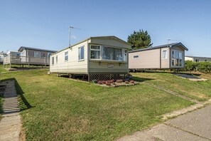 A mobile home with a fenced yard and a small garden.