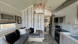 A compact living space with a sofa, patterned cushions, a kitchen area, and a patterned floor.