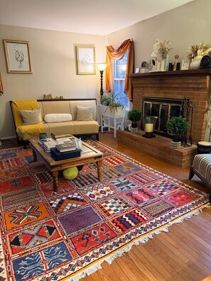 A living room with a sofa, coffee table, patterned rug, fireplace, and wall art. - World Cup 15 min: Sleeps 10, Pool, Near Airport (Bala Cynwyd)