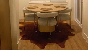 Una sala da pranzo con un tavolo rotondo, sei sedie e un tappeto marrone.