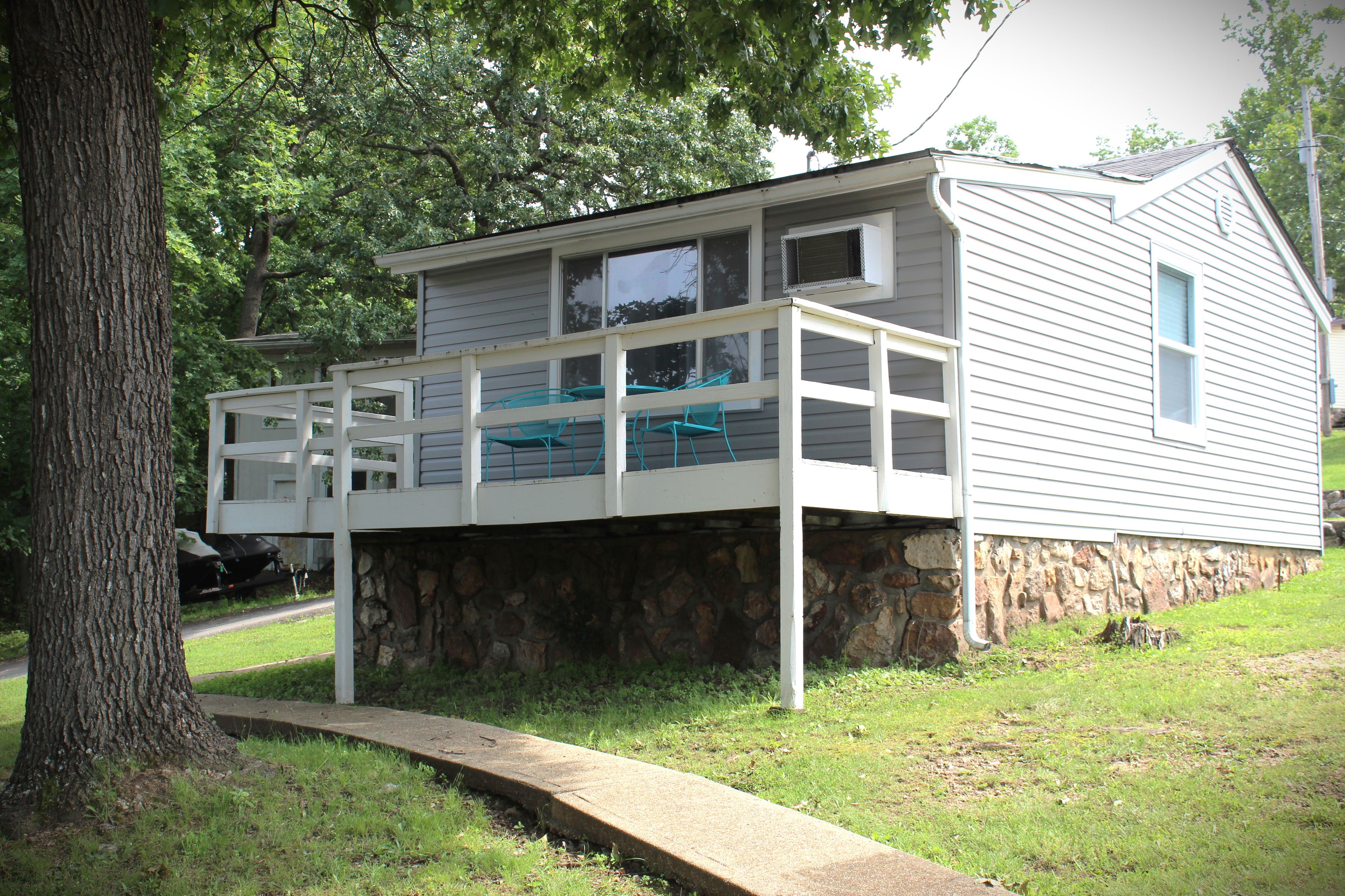 A two-story house with a stone foundation, a covered porch, and a small swimming pool.
