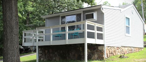 A two-story house with a stone foundation, a covered porch, and a small swimming pool.