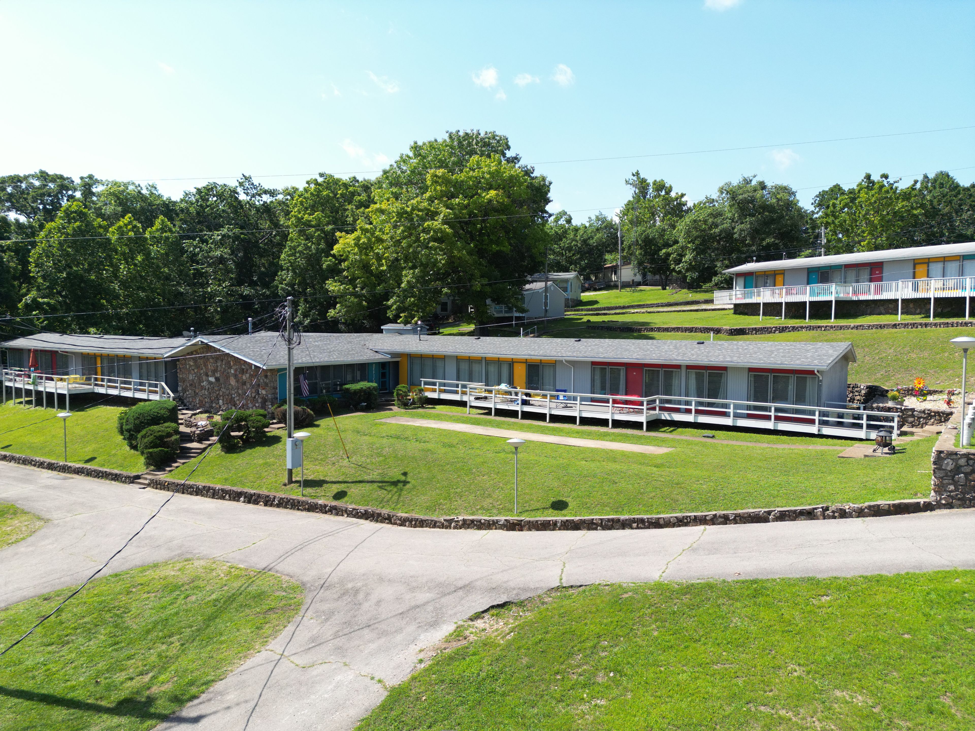 A motel with multiple rooms, a covered parking area, and a grassy lawn.