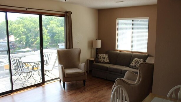 A living room with a sofa, armchairs, a dining table, and a large sliding glass door leading to an outdoor area.