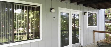A covered porch with a wooden deck, a number '35' on the wall, and a door with glass panels.