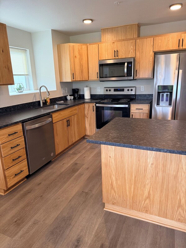 A modern kitchen with wooden cabinets, stainless steel appliances, and a granite countertop.