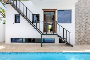 Une maison moderne dotée d’une piscine, d’un escalier et d’une porte donnant sur un espace intérieur.