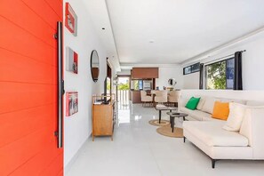 Un salon moderne avec un canapé blanc, une table basse et un coin repas avec des chaises.