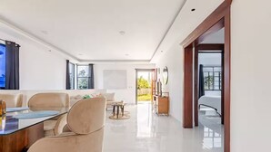 Un intérieur moderne comprenant un coin repas, un canapé et une vue sur l’extérieur, visible à travers une porte.