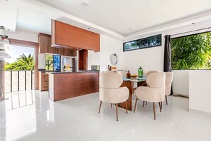 Une cuisine moderne dotée d’un îlot central, d’un coin repas avec quatre chaises et d’une grande fenêtre donnant sur un paysage verdoyant.